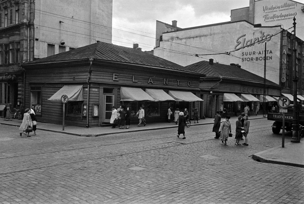 Aleksanterinkatu 9. - Kluuvikatu 5. Elannon myymälä ja Elannon suur-aitta. Puurakennukset purettiin syksyllä 1950 ja paikalle rakennettiin Elannon tavaratalo.