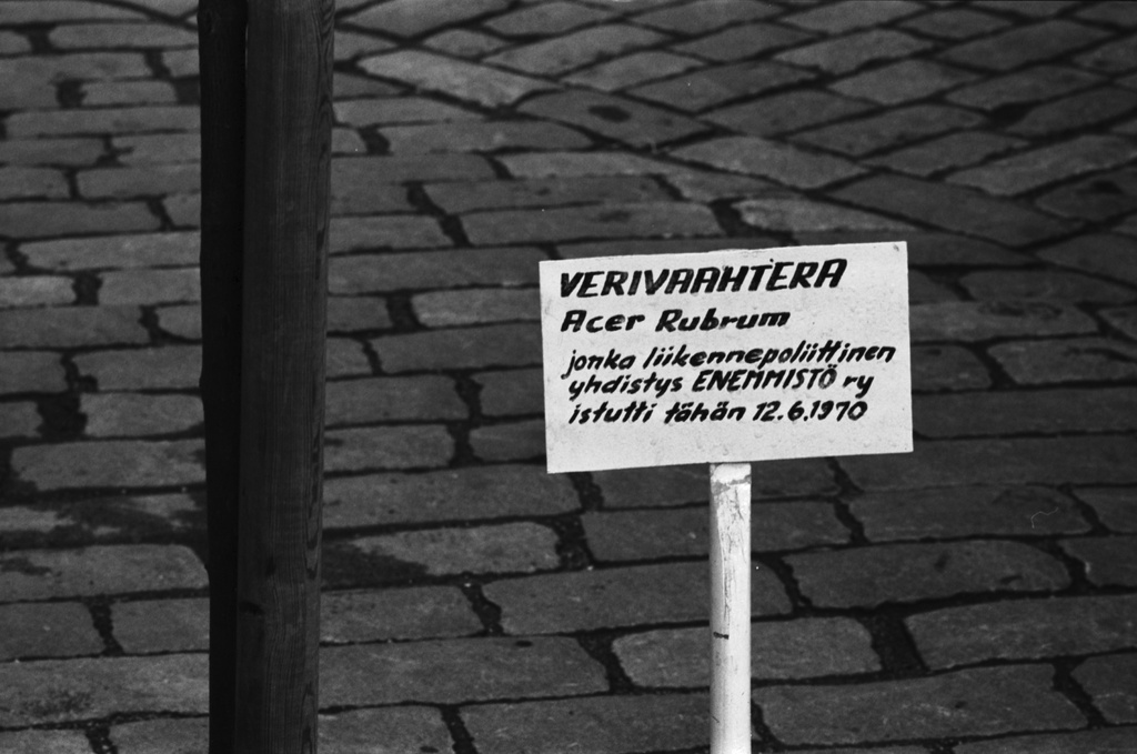 Aleksanterinkatu 52. Aleksanterinkadulla Stockmannin tavaratalon edustalla kyltti, jossa teksti: VERIVAAHTERA Acer rubrum jonka liikennepoliittinen yhdistys ENEMMISTÖ ry istutti tähän 12.6.1970.