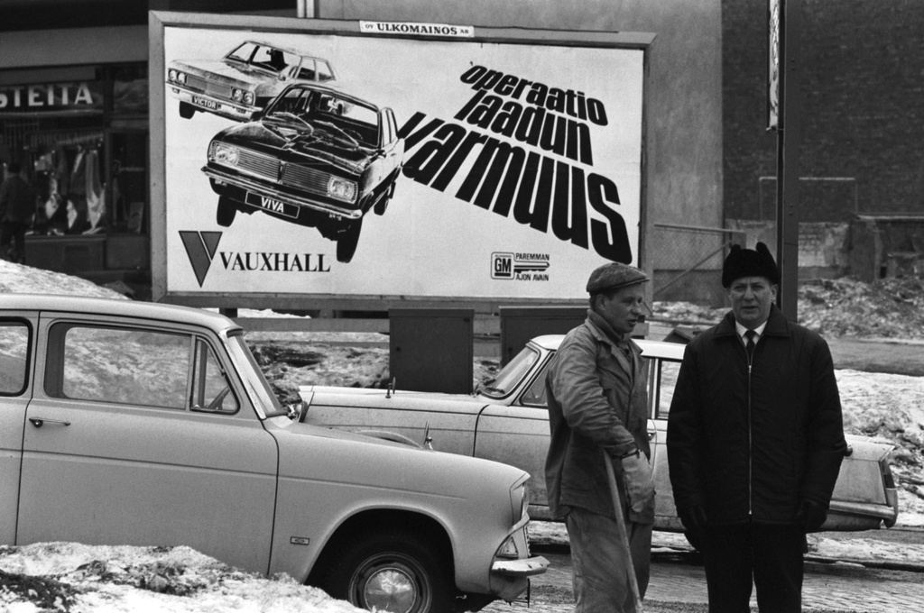 Porthaninkatu 1. Kaksi miestä, pysäköityjä autoja ja Vauxhall-automainos, (operaatio laadun varmuus) Porthaninkadun ja Toisen linjan kulmassa.