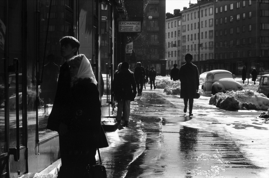 Runeberginkatu 59. Jalankulkijoita sulavan lumen kastelemalla Runeberginkadulla Töölöntorin kulmilla