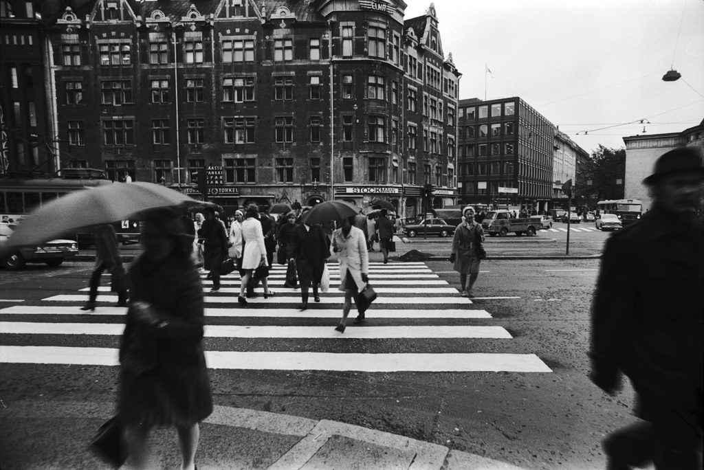 Mannerheimintie 1. Jalankulkijoita sadesäällä ylittämässä Mannerheimintietä Stockmannin Argoksen talon edustalla Pohjoisesplanadin kulmassa.