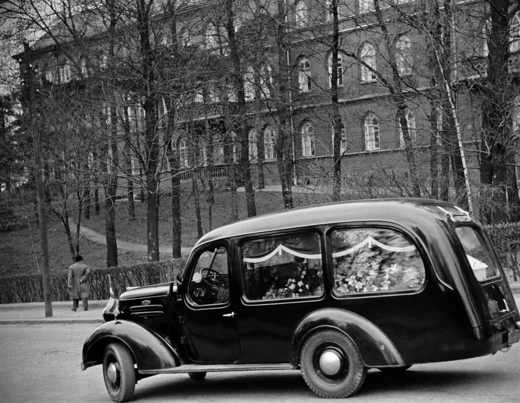 Helsingin Diakonissalaitos, Ester Svenssonin hautajaiset. Ruumisauto lähdössä Diakonissalaitoksen kirkossa tapahtuneen ruumiinsiunauksen jälkeen kohti hautausmaata. Seppelein ja kukin peitetty arkku auton takaosassa.