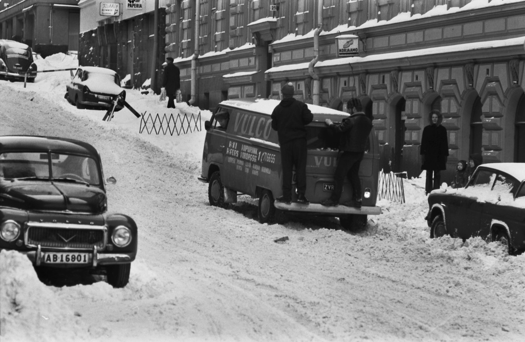 Meritullinkatu 25. Kaksi miestä seisomassa painona pakettiauton perässä lumisella Meritullinkadulla. Näkymä Liisankadulta Kruununhaankadun suuntaan.