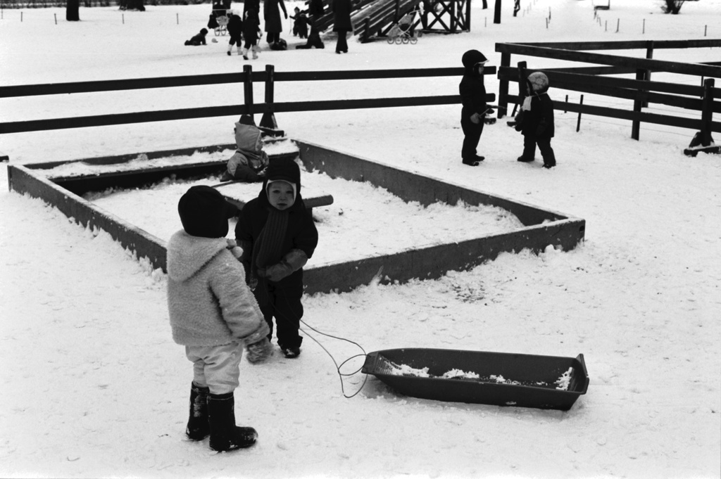 Kruununhaka, Liisanpuistikko. Lapsia pakkaspäivänä muovipulkan kanssa lumisessa Liisanpuistikossa. Taustalla betoninen hiekkalaatikko.