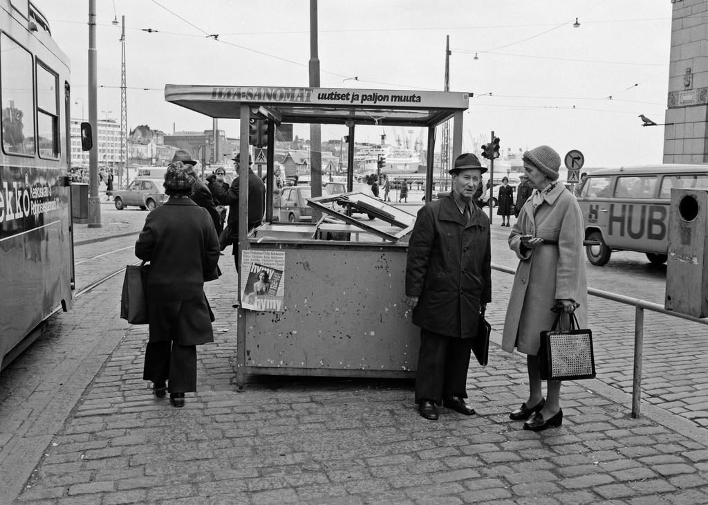 Ihmisiä raitiovaunupysäkillä Kauppatorilla vieressään vapunaattona tuhottu lehtikioski