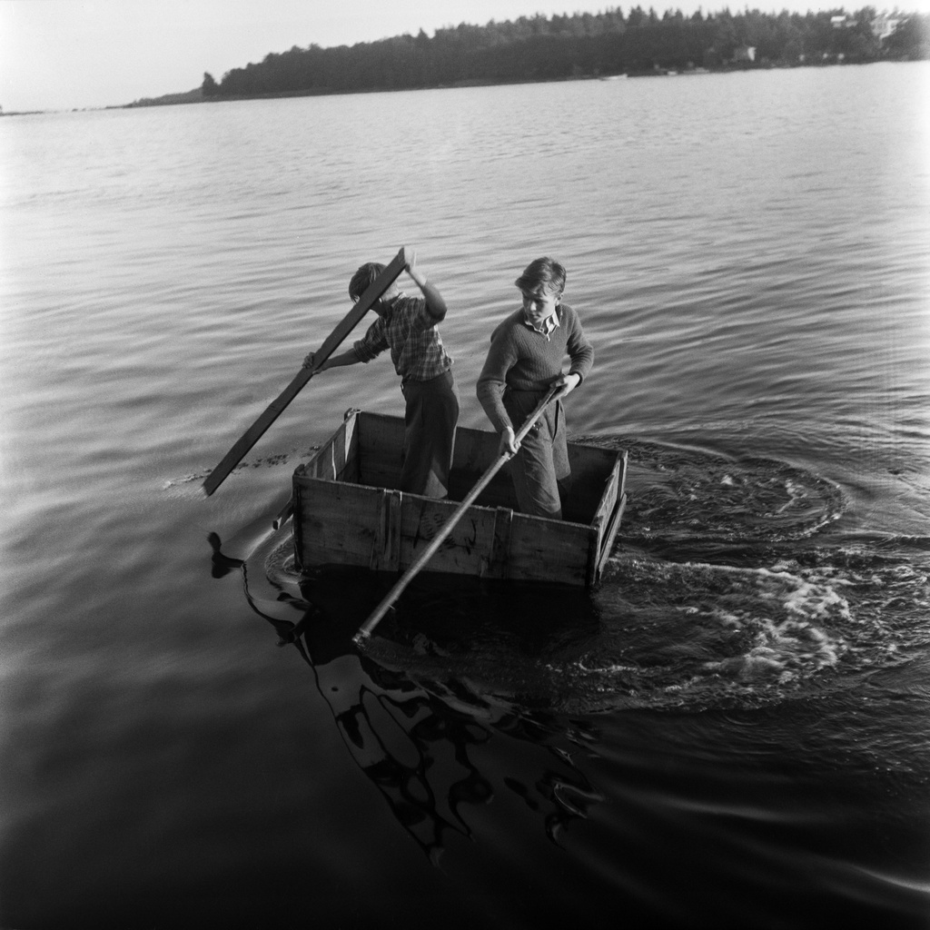 Poikia melomassa omatekoisella veneellä Lauttasaaren rannassa. Lohiapajanlahti.