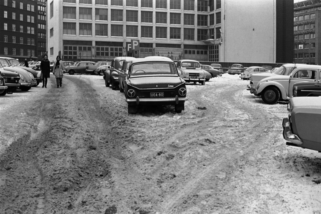 Fredrikinkatu 44. Autoja lumisella pysäköintipaikalla Kampin sähköaseman edustalla. Näkymä Autotalon suunnalta Kampintorille päin.