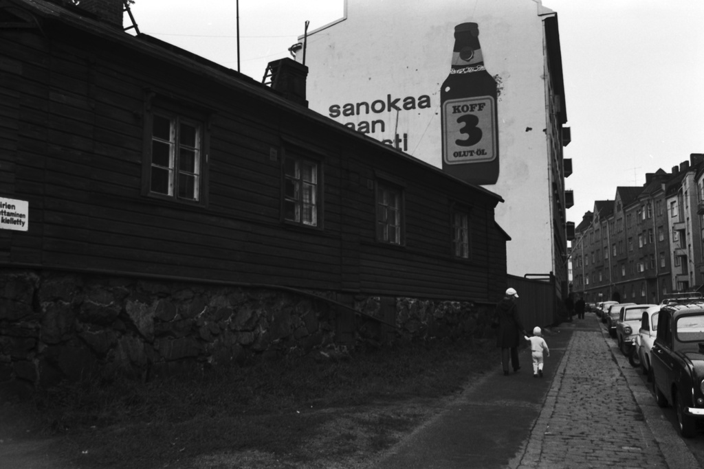 Punavuorenkatu 21, 19. Puutalo Punavuorenkatu 21:ssä. Taustalla Punavuorenkatu 19:n kivitalon päädyssä suuri Koff 3 -olutmainos. Näkymä koilliseen.