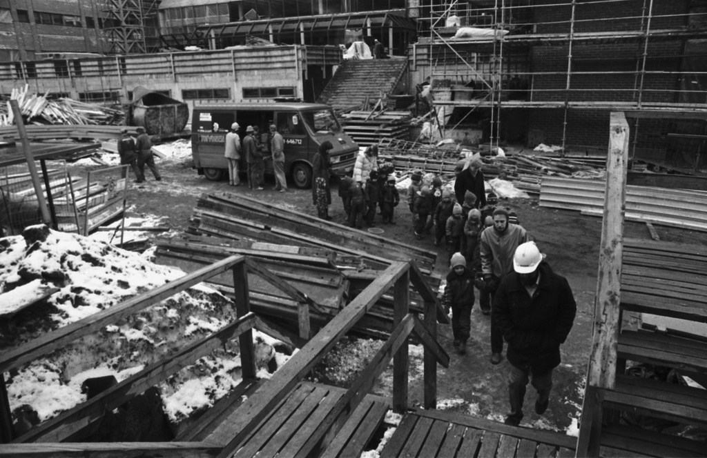 Ensi linja 3. Wallininkatu 2. Vironniemen päiväkodin lapset ja aikuiset tutustumassa Suomen Kaupunkiliiton toimitalon (Kuntatalon) rakennustyömaahan. Kierros on päättymässä ja ollaan siirtymässä työmaaruokalaan. Kuva Ensi linjan puolelta.