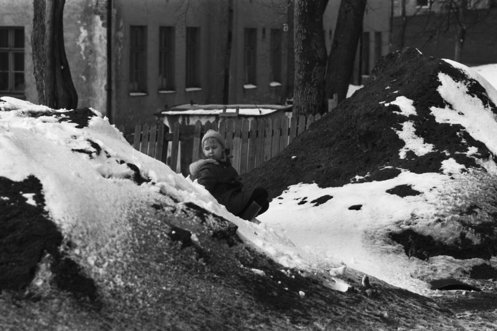 Lapinlahdenkatu 6. Tyttö kevätauringossa likaisten lumikasojen keskellä Lapinlahdenkadulla. Taustalla Lapinlahden koulu, joka purettiin 1970.