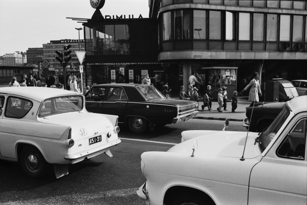 Siltasaarenkatu. Säästöpankinranta 2. Lastentarhan lapsia hoitajineen ylittämässä suojatietä jonossa narusta kiinni pitäen Säästöpankinrannan ja Siltasaarenkadun kulmassa matkalla Tokoinrannan puistoon. Etualalla kolme Ford Anglia -merkkistä henkilöautoa.