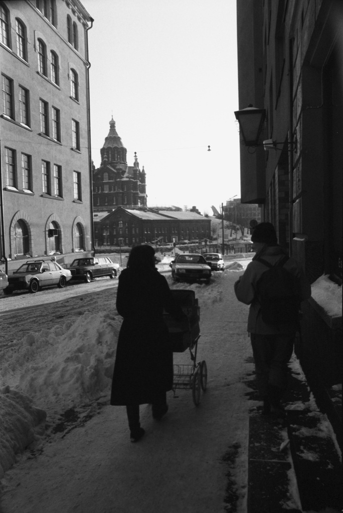 Meritullinkatu. Äiti (Etta Harvilahti) työntämässä lastenvaunuja lumisella Meritullinkadulla. Taustalla Uspenskin katedraali.