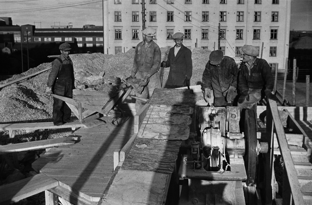 Maanrakennustöitä Torkkelinmäellä, todennäköisesti Helsingin toisen suomalaisen lyseon (nyk. Helsingin kuvataidelukio, ent. Torkkelin lukio) työmaa n. 1944. Käynnissä sepelimylly. Taustalla Pengerkatu 17. Vasemmalla taustalla OTK:n tehtaat.