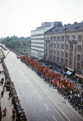 Elanto-lehti Helluntai 1957. Valtakunnallisen ammattiyhdistyslikkeen 50-vuotisjuhla. Kulkue Hakaniemessä Elannon edessä. Juhlakulkue marssi ammattiyhdistysliikkeiden lippujen johtamana viisitoistatuhantisena, juhlavana rivistönä läpi Helsingin. Pääjuhla pidettiin stadionilla.  similar photo