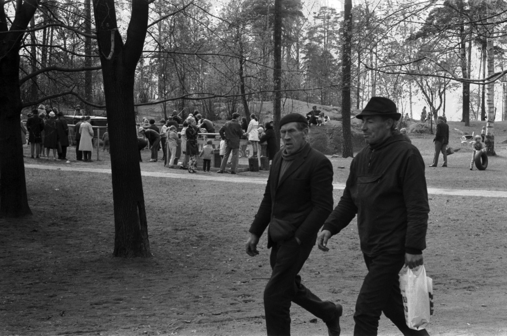 Sibeliuksen puisto. Helsingin juhlaviikot. Kaksi puistojen miestä muovikassin kanssa kävelemässä Sibeliuksen puistossa. Taustalla puistotapahtumaan osallistuvia ihmisiä.