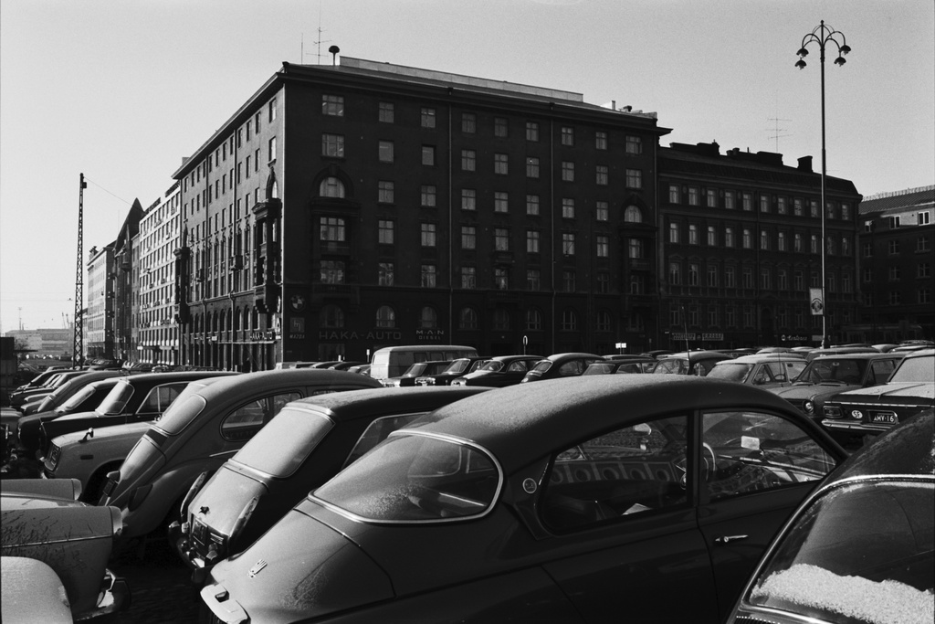 Kamppi, Hietalahdentori. Pysäköityjä, huurteisiä autoja Hietalahdentorilla. Taustalla Hietalahdenrannan ja Hietalahdenkadun kulmarakennus, jossa BMW, Mazda, Hanomag ja MAN -autoja myyvän Haka-Auton myymälä.