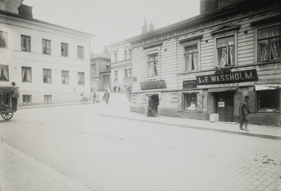 Vas. Hallituskatu 15 (nyk. Yliopistonkatu 5), oik. Kluuvikatu 7, jossa mm. S. Sundströmin lihakauppa sekä A & E. Wassholmin viinikauppa. Taustalla Vuorikatu 1.  duplicate photo