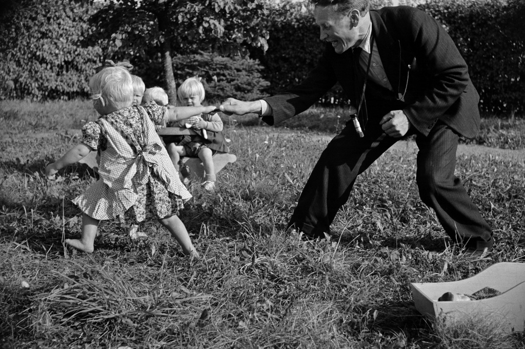 Tyttö leikkii valokuvaaja Väinö Kanniston kanssa Aunelan lastenkodin pihalla.