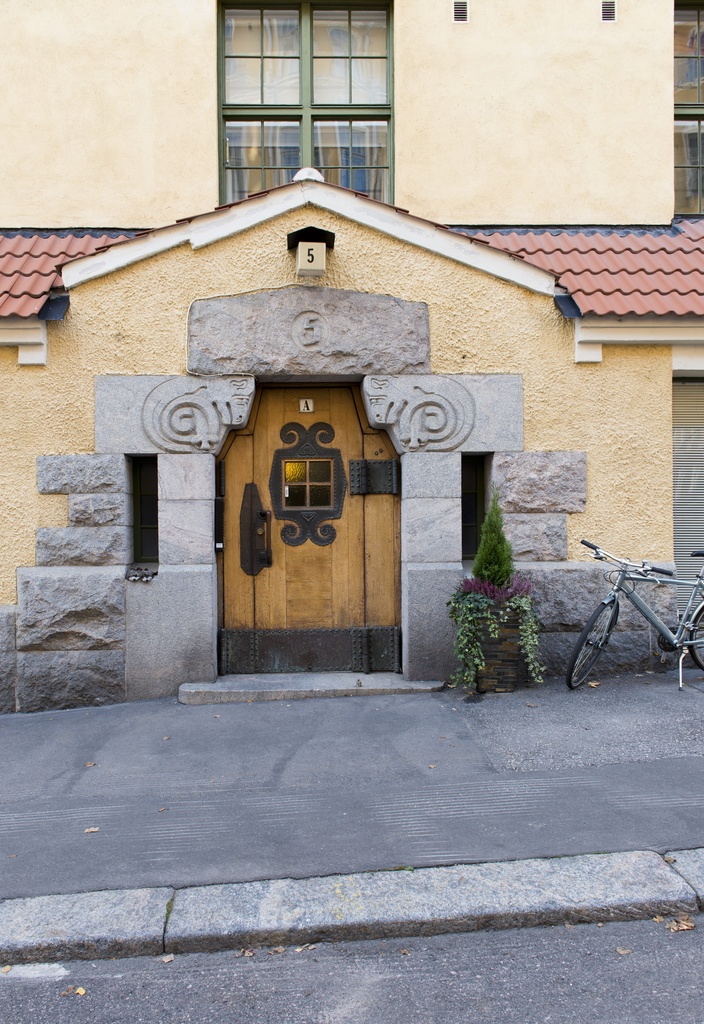 Kiinteistö Oy Eol, Luotsikatu 5 A. Arkkitehtitoimisto Gesellius, Lindgren, Saarinen. Sisäänkäynti. Jykevässä puuovessa koristeellisia takorautadetaljeja (helat, ikkunakehys) sekä värillisestä lasista valmistettu neliruutuinen ikkuna. Luonnonkiviportaali, jossa puskevat pässit. Vuonna 1901 suunniteltu talo on hyvä esimerkki alkuperäisessä asussaan säilyneestä Katajanokan art nouveau -kaupunginosan luonnonkivestä ja tiilestä rakennetusta asuintalosta.
