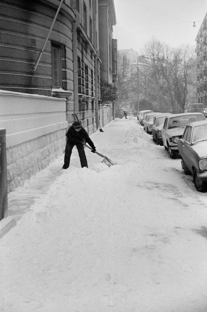 Ensilumi Töölössä vuonna 1973. Lumitöitä Museokadun ja Oksasenkadun risteyksessä sijaitsevan Karhu-talon edustalla, Oksasenkadun puolella. Taka-alalla näkymä Apollonkadulle ja Mika Waltarin puistoon.