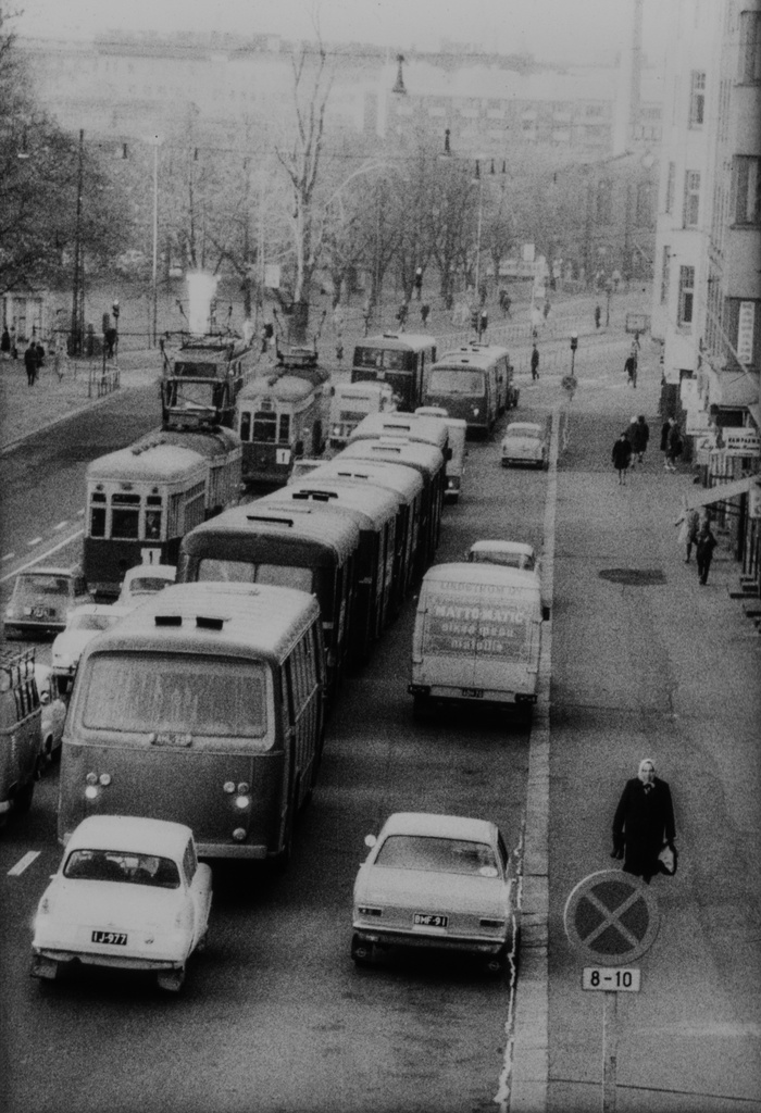 Liikennettä Hämeentiellä, muun muassa busseja ja raitiovaunuja. Oikealla Hämeentie 34, 32, 30.