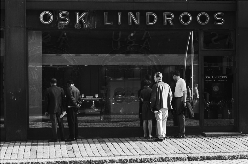 Aleksanterinkatu 48. Ihmisiä Osk. Lindroosin kultasepän liikkeen näyteikkunan edessä Aleksanterinkadulla kävelykatukokeilun aikaan.