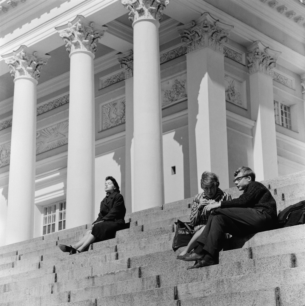 Ihmisiä istumassa Tuomiokirkon portailla.