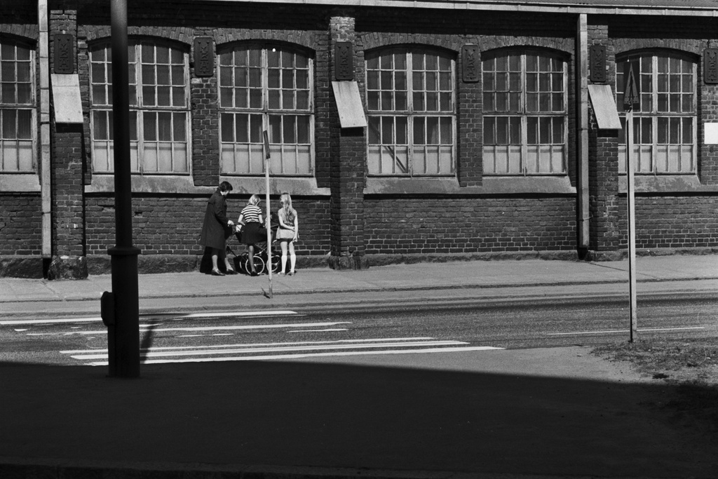 Sörnäisten rantatie 9-11. Lastenvaunuja työntävä nainen ja pari lasta Hakaniemen sillan päässä olevan Oy Wärtsilä Ab:n, entisen Kone- ja Siltarakennus Oy:n teollisuusrakennuksen seinustalla.