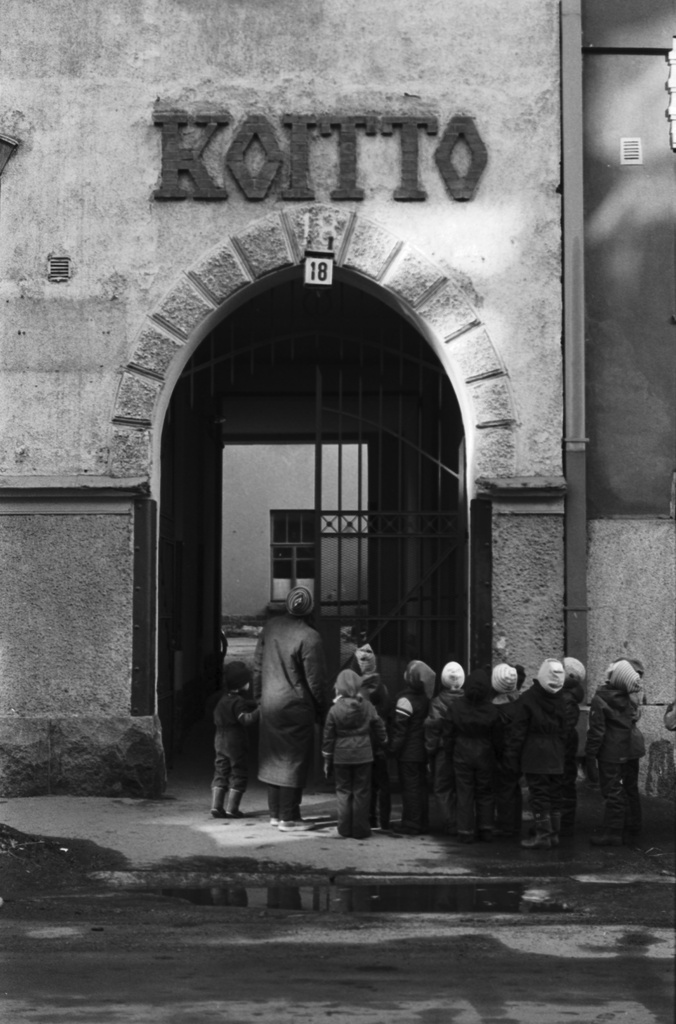 Luotsikatu 18. Vironniemen päiväkodin lapsia ja aikuisia Luotsikatu 18:n Koiton talon porttikäytävän edustalla tutustumassa Katajanokan jugend-rakennuksiin.