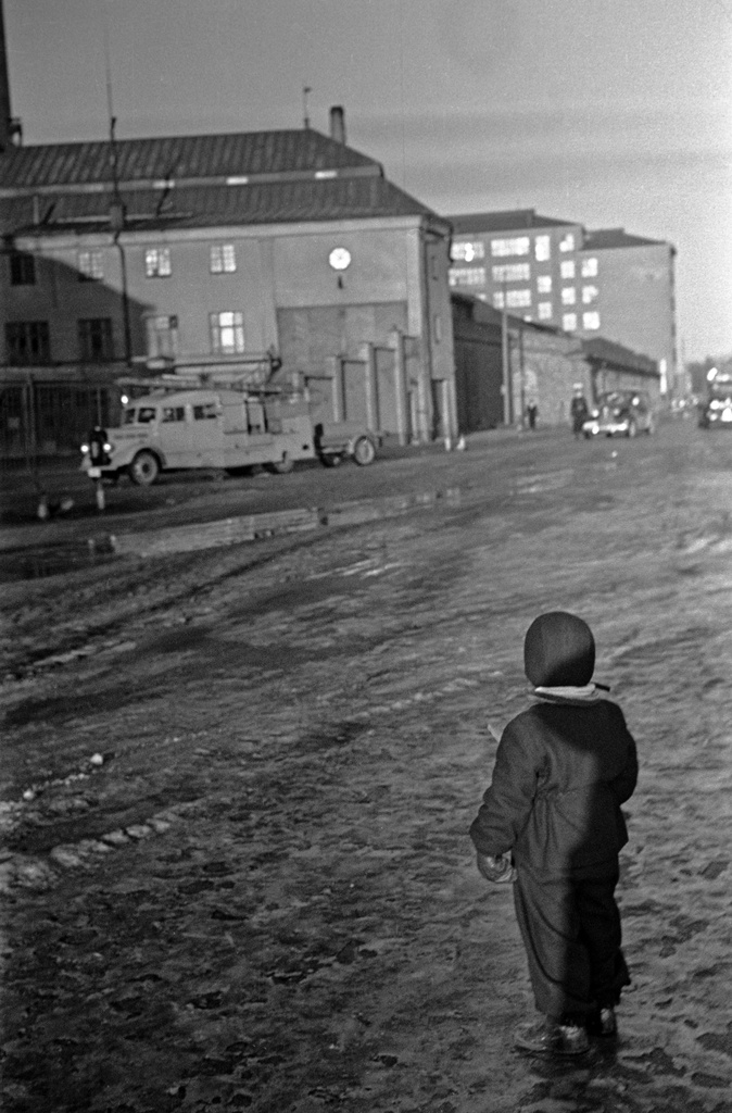 Sörnäisten rantatie 25 - 27. Lapsi kuraisella kadulla. Taustalla teollisuusrakennuksia ja autoja.