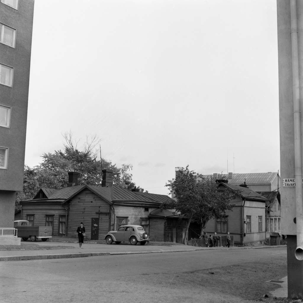 Violankatu 2:n tontilla sijainneet puurakennukset nykyisen puiston paikalla. Vasemmalla Violankatu 2 - Hämeentie 95 kerrostalon päätyä. Kadulla ryhmä koulupoikia ja rahastajan virka-asuun pukeutunut nainen sekä pysäköidyt Volkswagen- ja Moskvitsh -autot. Taustalla oikealla erottuu Violankatu 4 - Helminkatu 7:n kerrostalon katto