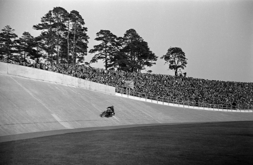 Velodrom, Helsingin pyöräilystadion, moottoripyöräkilpailut. Moottoripyörä radalla, taustalla katsomo.