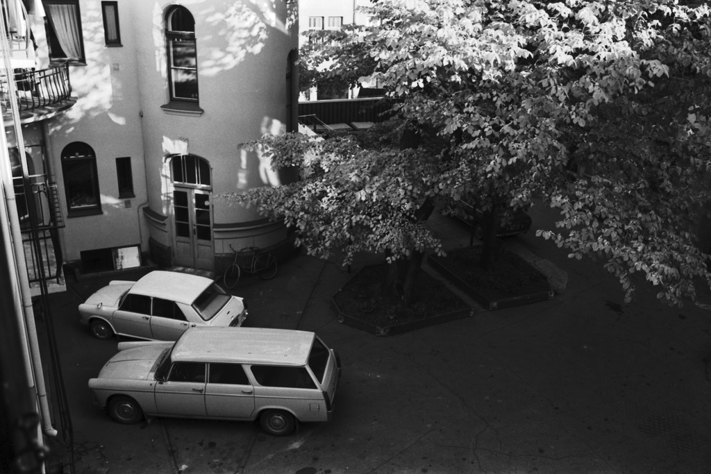 Ullanlinna, Tehtaankatu 6. Kerrostalon pihalla Ullanlinnassa puita sekä pysäköityjä autoja, lähimpänä Austin/Morris 1100/ 1300 ja Peugeot 404 Break/Familiale.