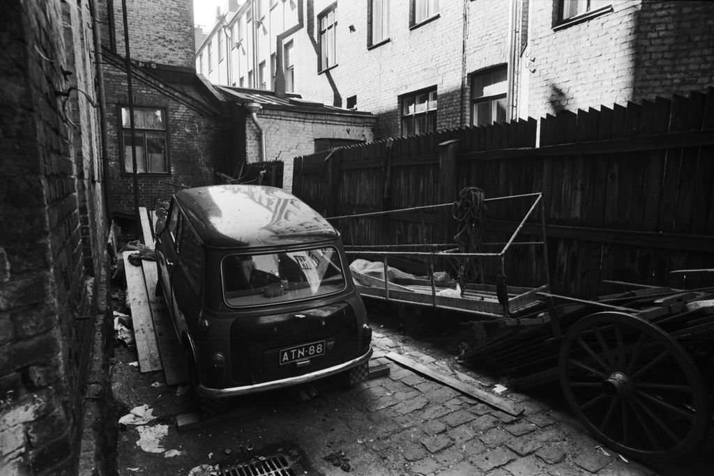 Fabianinkatu 8. Viritettävänä oleva Morris Mini, maalalarinkelkka ja torikärryt ränsistyneellä pihalla Fabianinkadulla.