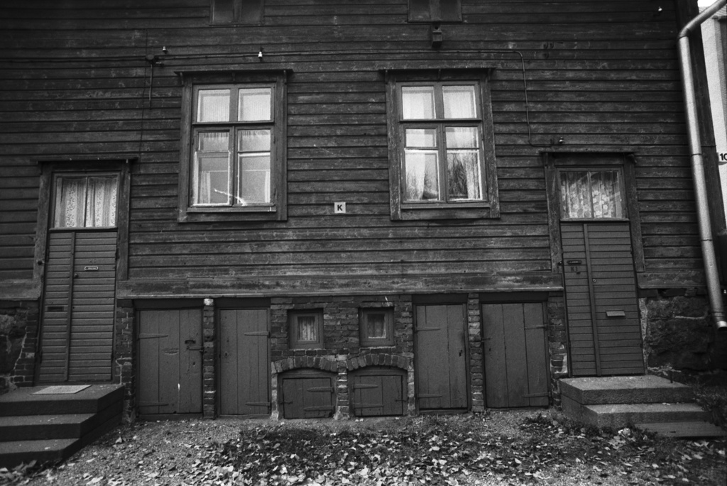 Lastenkodinkatu 2-10. Ruoholahden sadan markan villat, puutalon pihan puolen julkisivua. Korkeassa kivijalassa kahden asunnon sisäänkäynnit asuntoihin sekä omiin käymälöihin ja kellareihin.