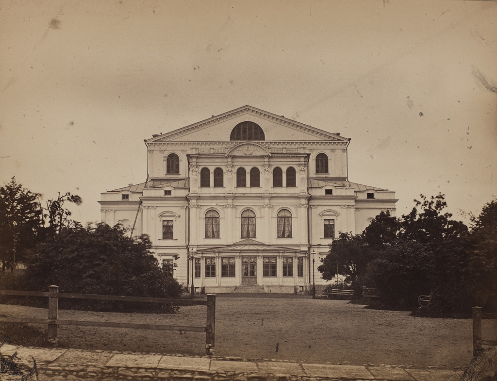 Kuvan alle pohjustuspahviin painettu teksti "Nya theatern". Kuvan alla, sen vasemman alakulman alle on pohjustuspahviin painettu teksti "Photogr. af C.A. Hårdh". Uusi teatteritalo (Nya teatern), nykyinen Ruotsalainen teatteri, valmistunut v. 1866, Esplanadin puiston puolelta katsottuna.