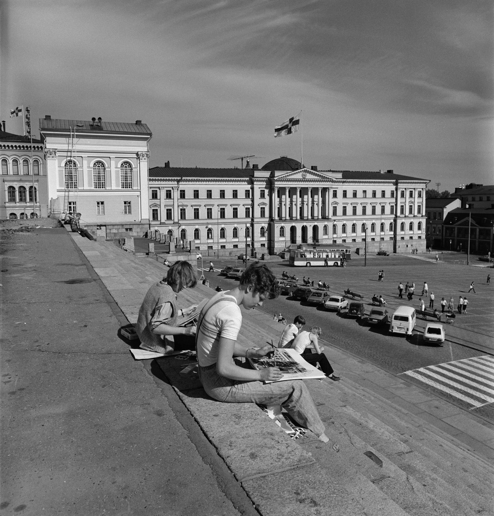 Ihmisiä istumassa Tuomiokirkon portailla.