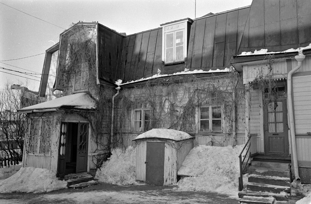 Puisen asuinrakennuksen pihan puoleinen julkisivu Valllilantiellä Puu-Vallilassa. Rakennuksen ulkoseinillä kasvaa köynnöskasvia.