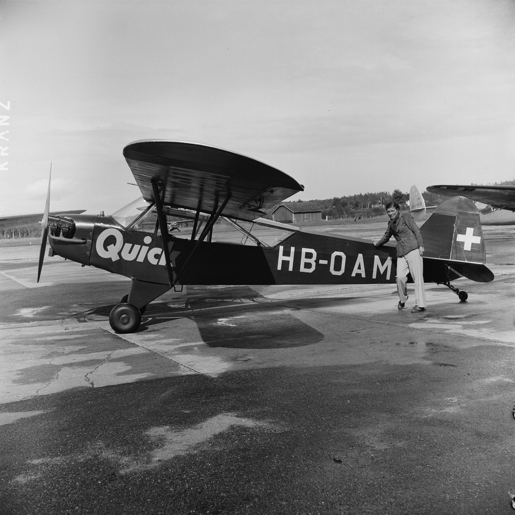 Helsingin olympialaiset 1952. Saksalaisen Quick-lehden pienkone Malmin lentokentällä.  Kuvassa todennäköisesti Elly Beinhorn "lentävä reportteri". Beinhorn saavutti jo ennen toista maailmansotaa kuuluisuutta eräänä taitavista saksalaista lentäjänaisista. Koska hän halusi jatkaa lentämistä myös sodan jälkeen, joutui hän Saksan lentokiellon takia ostamaan koneen Sveitsistä (kuvan amerikkalaisvalmisteisen Piper J-3C-65 Cub -koneen, rekisteritunnukseltaan HB-OAM) ja lentämään sillä, kunnes pystyi rekisteröimään koneen Saksan rekisteriin.