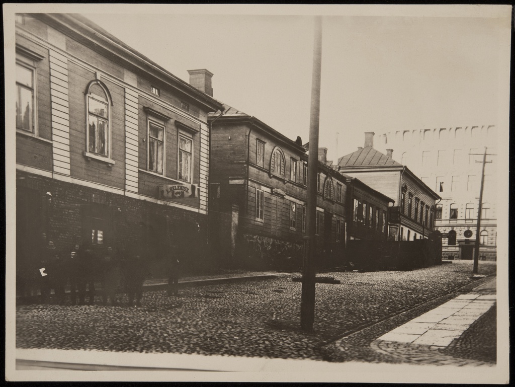 Rikhardinkatu 2, 4, taustalla Korkeavuorenkatu 30. Etualalla vasemmalla ryhmä lapsia, Rikhardinkatu 2:ssa suutari A. Heleniuksen mainoskyltti ja toimitilat.