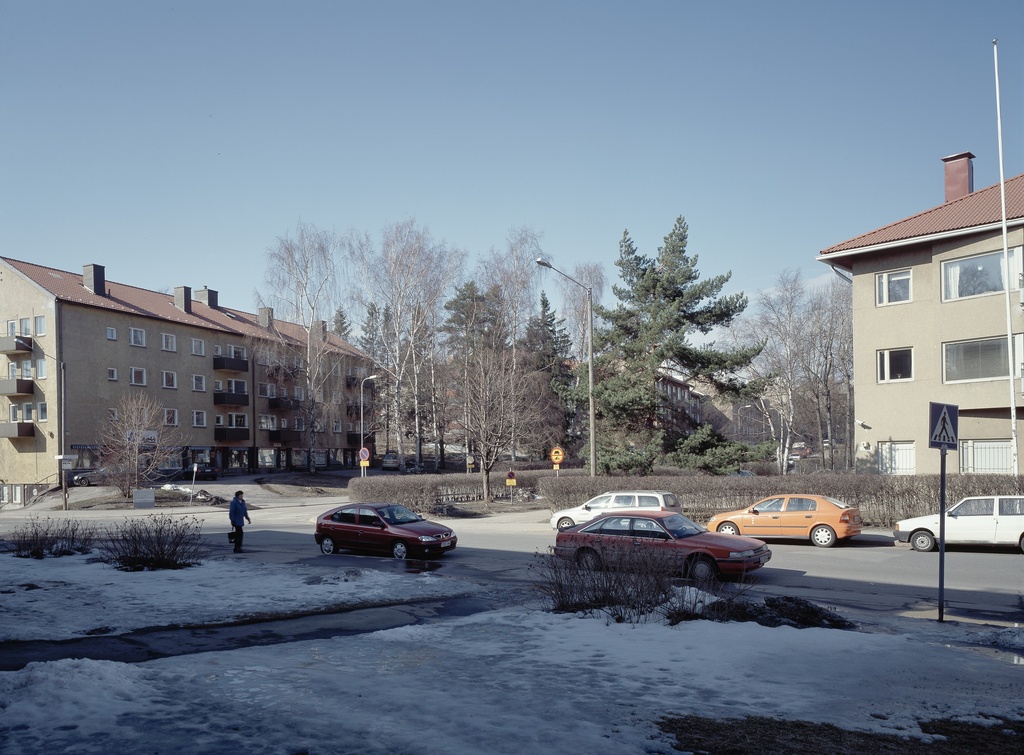 Pastori Jussilaisen tien alkupää nähtynä Aino Acktén tieltä.  Vasemmalla Pastori Jussilaisen tie 1- Aino Akctén tie 8, oikealla Pastori  Jussilaisen tie 2- Aino Akctén tie 10.