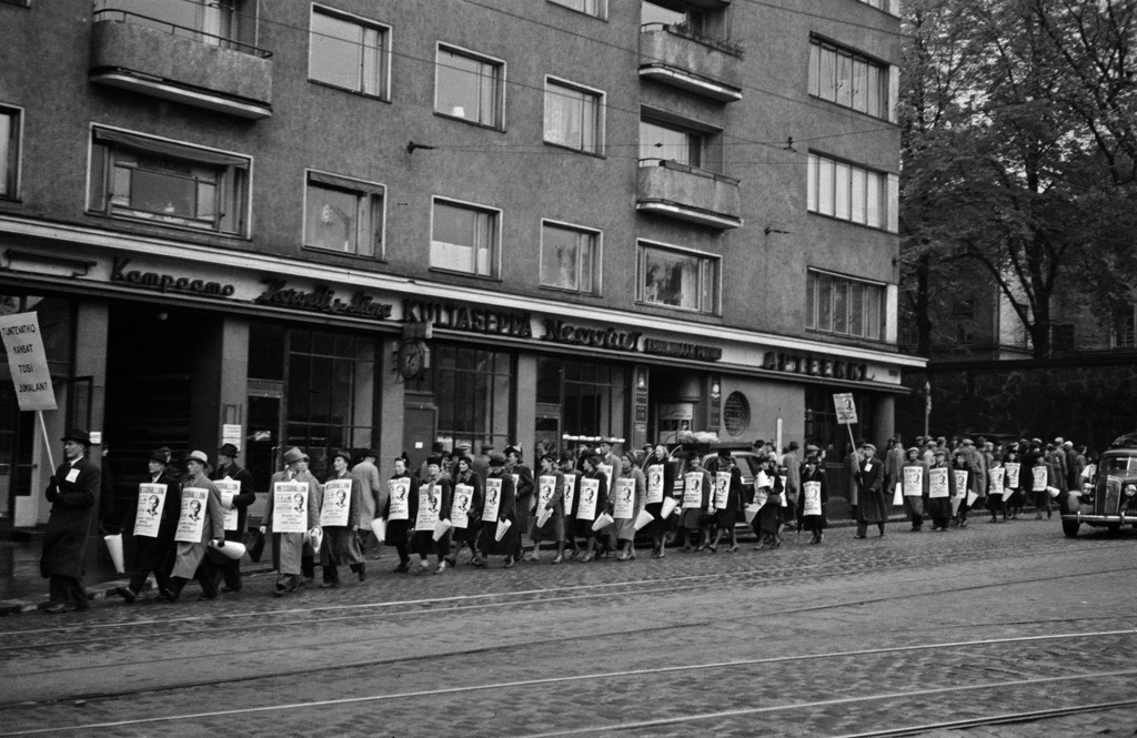 Jehovan todistaja, insinööri Kaarlo Hartevan esitelmää mainostava kulkue. Miehiä ja naisia mainos- ja tekstikylttien kanssa Unioninkatu 39:n kohdalla.