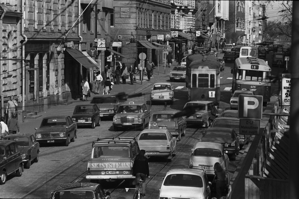 Liisankatu. Iltapäivän ruuhkaliikennettä Liisankadulla Kaisaniemen puoleisessa päässä. Keskellä linjan 1 ruuhkavuoron vanha kaksiakselinen raitiovaunu perävaunun kera. Näkymä kiviaidan päältä itään Snellmaninkadun suuntaan.