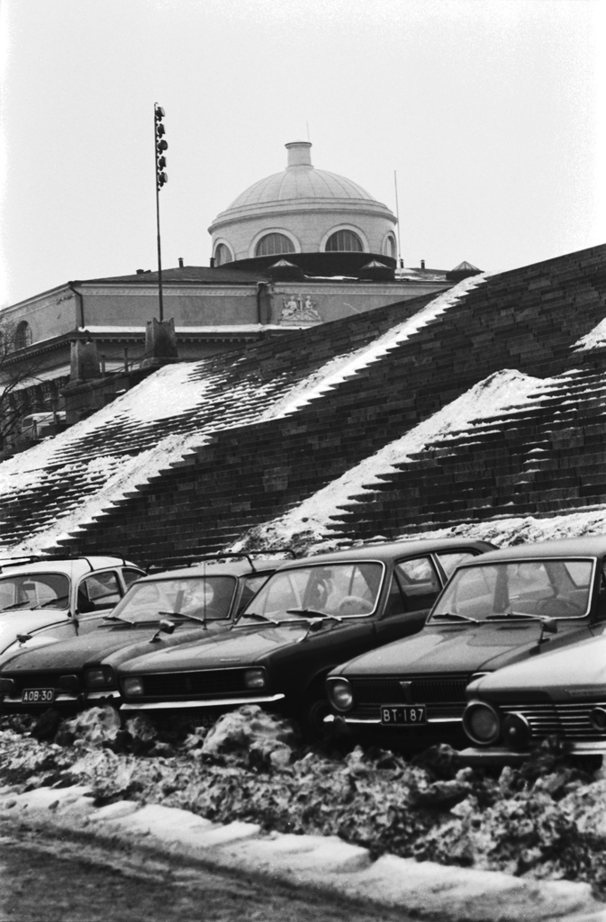 Kruununhaka, Hallituskatu 7. Loskaa sekä pysäköityjä autoja Hallituskadulla Tuomiokirkon portaiden juuressa. Taustalla Helsingin yliopiston kirjaston kupoli.