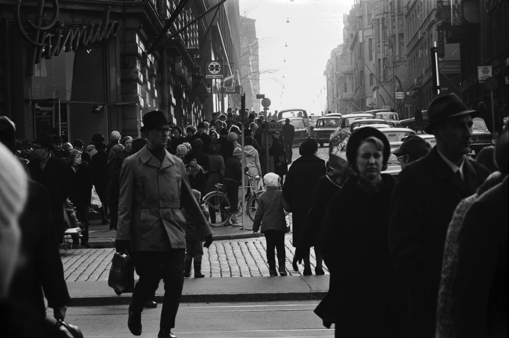 Kamppi, Kalevankatu. Jalankulkijoita ns. Primulan kulmassa ruuhka-aikaan ylittämässä Mannerheimintietä. Kalevankadulla sankoin joukoin ihmisiä. Näkymä Stockmannin tavaratalon kulmalta lounaaseen.