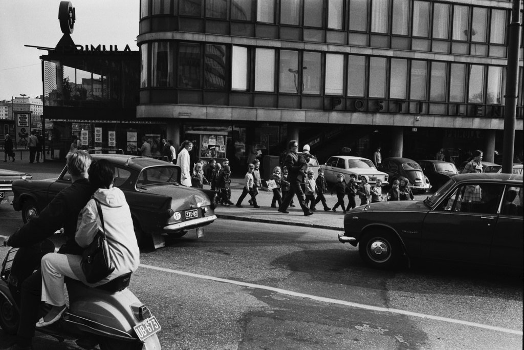 Säästöpankinranta 2. Lastentarhan lapsia hoitajineen jonossa narusta kiinni pitäen Säästöpankinrannassa matkalla matkalla Tokoinrannan puistoon. Etualalla skootteri, jossa nainen kyydissä sekä Ford Anglia, jossa perä vähän lytyssä.