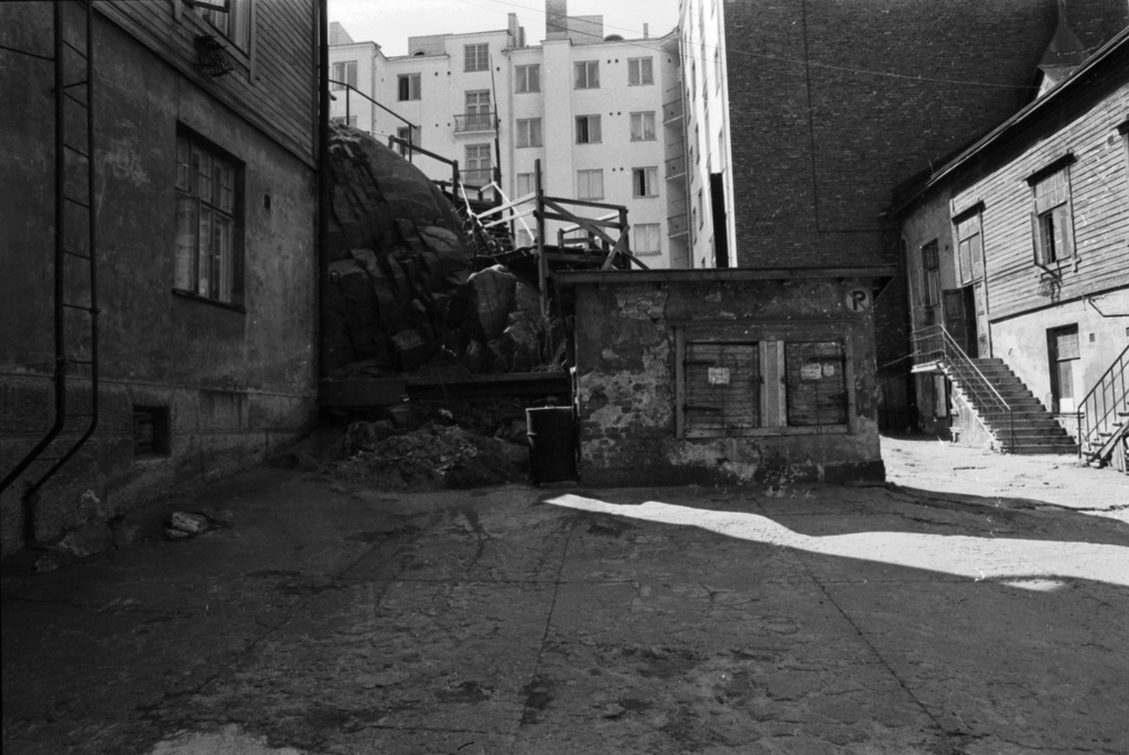 Fleminginkatu 16. Näkymä Fleminginkatu 16:n ränsistyneelle pihalle. Oikealla puutalo, keskellä likaämpärikaivot, taustalla korkealle kalliolle johtavat portaat.