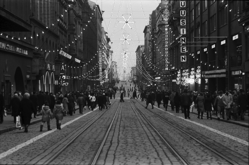 Aleksanterinkatu. Ostoksilla olevia ihmisiä joulukadulla Aleksanterinkadun kävelykatukokeilun aikaan. Katuun maalatut valkoiset viivat rajaavat jalankulkijoille varattua aluetta. Näkymä Keskuskadun kulmasta itään Senaatintorille päin.