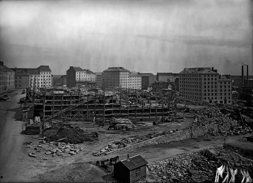 Agricolankatu 1-3. Helsingin Teollisuuskoulun työmaa (myöhemmin Helsingin teknillinen opisto / oppilaitos, nykyisin Metropolia Ammattikorkeakoulun opetuspiste). Työmaalla näkyy Oy Tektor Ab :n kyltti. Rakennukset taustalla, vasemmalta: Torkkelinkatu 13, 11, 9, 7, 5. Franzeninkatu 5. Franzeninkatu 1 / Pengerkatu 18. Pengerkatu 25. Pengerkatu 23 / Torkkelinkatu 3. Pengerkatu 17 / Sakarinkatu 3. Pengerkatu 23 ja 17 välissä puutaloja, joiden takana kauempana rakennukset: Hämeentie 23, Vilhovuorenkuja 18, 20.
