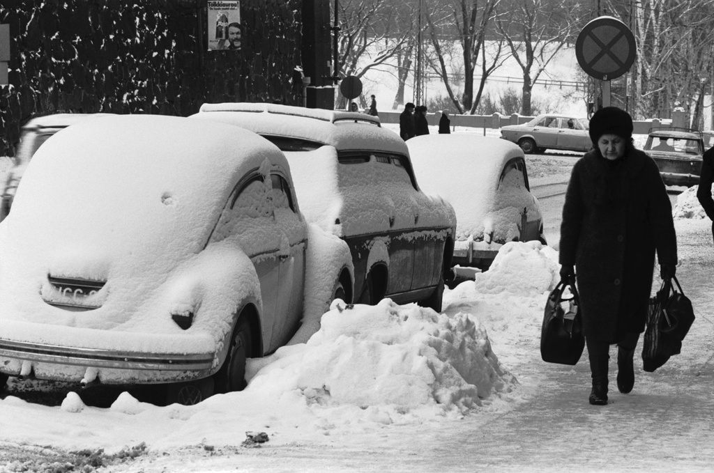 Kruununhaka, Liisankatu. Jalkakäytävällä kasseineen kävelevä nainen ja lumen peittämiä autoja Liisankadulla Kaisaniemenpuiston puoleisessa päässä.